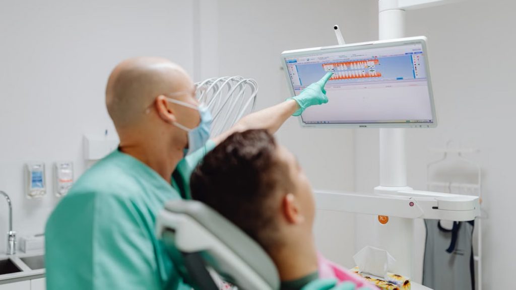 Dentist examining patient with dental imaging software in modern clinic.
